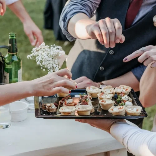 group-of-friends-eating-finger-food-at-a-wedding-r-BFUVP52